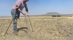 A farmer sifts the soil of one of his dry fields.
