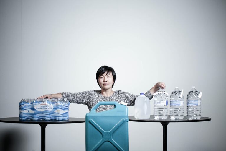 OPB production resource manager Lisa Miyamoto stands 14 gallons of water, collected as an earthquake preparedness exercise.