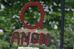 In this May 14, 2020, file photo, a person carries a sign supporting QAnon during a protest rally in Olympia, Wash, USA. The social media company Twitter said Tuesday Jan. 12, 2021, it has suspended more than 70,000 accounts associated with the far right QAnon conspiracy theory following last week's U.S. Capitol insurrection.