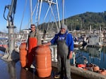 Nedian deckhand Joe Bentley, left, and Capt.Hank Slavens stand with salmon barrels after they unloaded their catch in Garibaldi, Ore. on April 29, 2026.