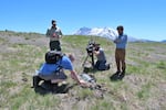 In summer of 2023, Scott Kemery investigates an engine buried under the ash of the 1980 eruption of Mount St. Helens with Matt Mawhirter of the U.S. Forest Service, left, while cinematographer Todd Sonflieth and producer Ian McCluskey, right, film for OPB's "Oregon Field Guide" television program. Kemery hopes it may be a clue that leads to more information on the whereabouts of Gerry Martin, a volunteer emergency radio operator who died in the eruption.