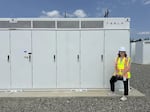 Snohomish County program manager Jessica Spahr stands alongside the nearly completed Tesla-made battery energy storage system in Arlington. The system is expected to go online this fall to add capacity to the electric grid in support of low-emissions renewable power sources.