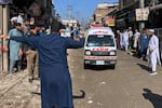 A volunteer clears the way for an ambulance transporting injured school children following a roof collapse at a private school in Peshawar, Pakistan, Thursday, Oct. 15, 2026.