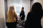 Valaria Zayas (left) and Dulce Volantin (center) walk down the hallway of their apartment building with case manager Hannia Centeno.