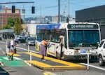 People cross the bike lane to board a TriMet bus on Southeast Hawthorne Boulevard, July 9, 2024. Hawthorne was modified to include parking-protected bike lanes and a bus and turn lane in summer 2021. 