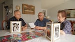 Anthony Veliz (L) Rodolfo Veliz and Candelaria Veliz (R) browse through family photos from the Colegio César Chávez days at their house in Salem, Oregon on July 30, 2024.