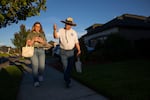 A woman and man walk down a suburban sidewalk looking at their phones.
