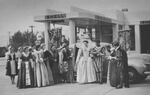 A group of actors with Lillian Davis as "Queen Elizabeth" stop for gas in the 1930s