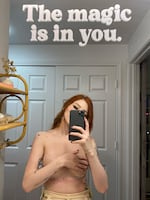 Abigail Glavy takes a selfie in a mirror. She is not wearing a shirt and covers her breasts with her arm. The picture has a headline that says, "The magic is in you."