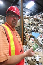 Keith Ristau, President of Far West Fibers, pulls a disposable coffee cup out of a pile of curbside recycling.