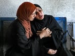 A woman comforts another mourning outside the morgue of al-Shifa hospital in Gaza City on Oct. 12, 2023.