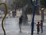 Kids play in a splash pad at Riverview Park on Wednesday in Mesa, Ariz. Experts warn to make sure any outdoor play time includes plenty of water and shade — and breaks from the heat — during an extended heat wave. 