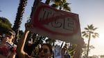 A demonstrator holds up a sign as they protest in front of the main entrance of Dodger Stadium on Thursday.
