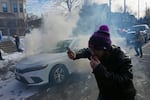 Protesters try to avoid tear gas dispersed by federal agents, Monday, Jan. 12, 2026 in Minneapolis.
