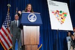 Agriculture Secretary Brooke Rollins speaks from behind a lectern on January 8. Health Secretary Robert F. Kennedy Jr. stands behind her. On the right side of the frame is a poster standing on an easel. The poster says "Dietary Guidelines for Americans" at the top and shows an inverted pyramid that has meats, vegetables and dairy at the top, with carbohydrates at the bottom.