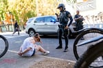 Portland Police Officer Donny Mathew checks a timer on his phone, waiting for treatment providers to arrive after arresting a woman for  drug possession in downtown Portland, Sept. 10, 2024. 