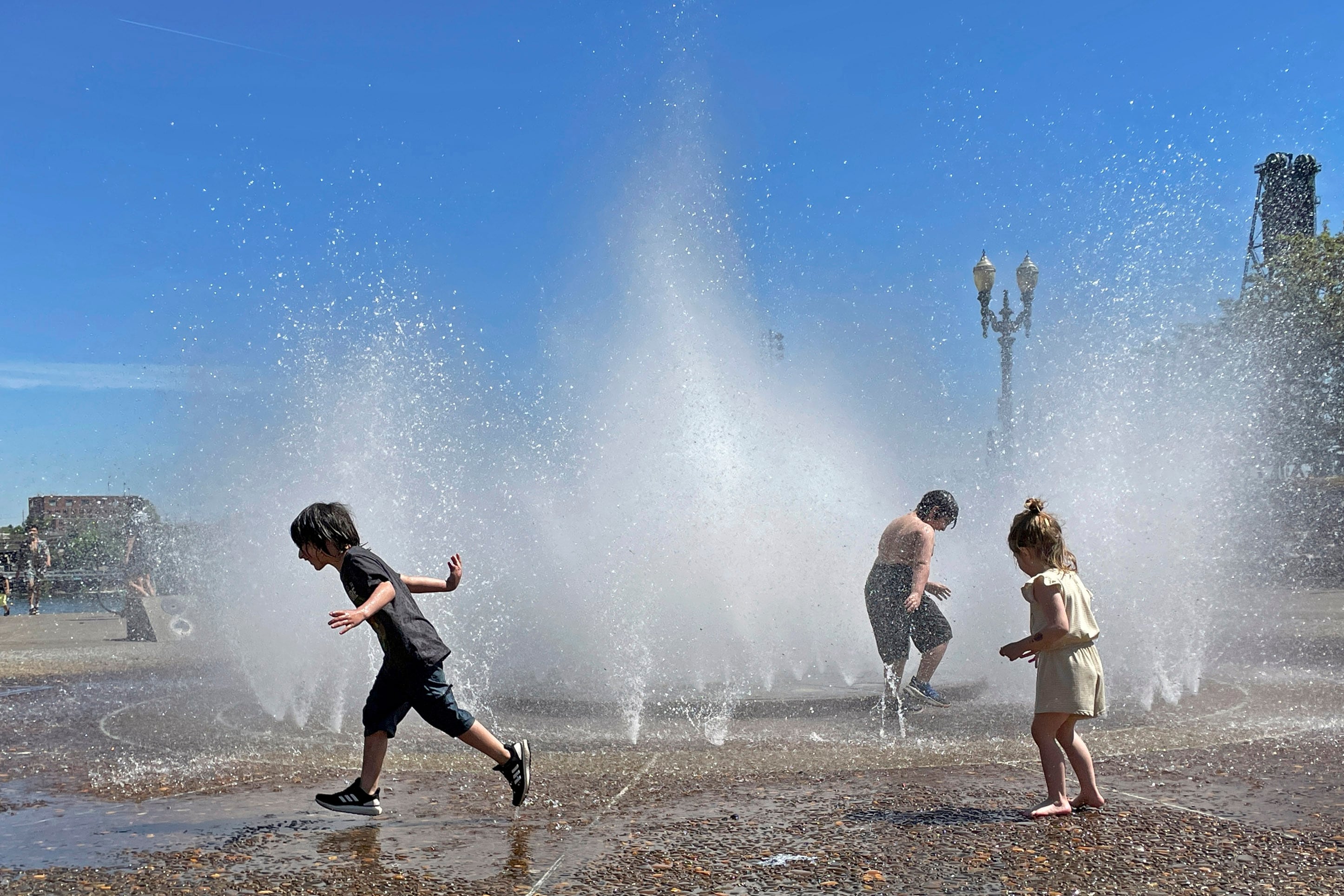 FILE: Children play in a fountain to cool off in downtown Portland, Ore., Friday, May 12, 2023.