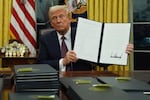 President Donald Trump holds up an executive order commuting sentences for people convicted of Jan. 6 offenses in the Oval Office of the White House, Monday, Jan. 20, 2025, in Washington.