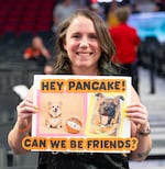 Liz Marx poses for a portrait with a sign for her dog, Billie, and Pancake.