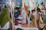A pediatrician instructs a mother on how to feed her baby, who is sick with measles, to improve her nutrition and aid in recovery. The child is a patient at DNCC Hospital in Dhaka, Bangladesh, which has been overwhelmed with measles patients.