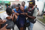 A woman cries as others hold her up.