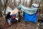 Jose Ortiz unlocks the gate to the residence he built in the homeless encampment known as the Jungle on Monday, Dec. 7, 2020, in Ithaca, N.Y.. His friend Tas'a Towsley is with him.