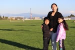 Wendi Suni Yah Canul poses with her children Mario Valle Yah (6) and Kiara Edila Valle Yah (8) with the Owens-Brockway glass recycling facility in the background in Northeast Portland's Cully Park on Oct. 7, 2021.