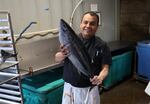FILE - Local Ocean sous chef Enrique Garcia holds a tuna ready to be filleted. The head, bones, and skin will be made into usable products.