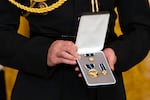 An official holds medals during an event for President Joe Biden to award the Presidential Citizens Medal to recipients in the East Room at the White House, Thursday, Jan. 2, 2025, in Washington.