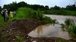 In this image made from video, people look at level of Canovanas river following heavy rain caused by the storm in Alto Trujillo, Puerto Rico, Thursday, July 30, 2020. Tropical Storm Isaias knocked out power and caused flooding and small landslides across Puerto Rico and the Dominican Republic on Thursday as forecasters predicted it would strengthen into a hurricane while moving toward the Bahamas and U.S. East Coast.
