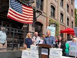 Bob Simril, center, speaks at a press conference July 6, 2026, in Portland, Ore., announcing Safer Portland had cleared the signature requirements for the November election. The proposal aims to hire more police officers using Portland's Clean Energy Fund.