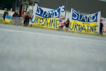 Protesters hold up Ukrainian flags outside Joint Base Elmendorf-Richardson as Trump and Putin meet in Anchorage.