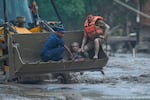 Rescuers use an earthmover to carry a victim of flash flooding to safety along the Trishuli River in Nepal's Nuwakot district, Wednesday, Aug. 26, 2026.