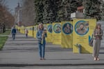 People walk down the street along banners commemorating fallen soldiers in Zaporizhizha.