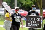 A protester holds a sign that reads "Justice for Manny" in this June 5, 2020 file photo in Tacoma, Wash., during a protest against police brutality. On Thursday, May 27, 2021, the Washington state attorney general filed criminal charges against three police officers in the death of Manuel Ellis, a Black man who died after telling the Tacoma officers who were restraining him he couldn't breathe.