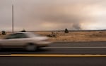 A car passes on U.S. Highway 26 as the Bench Fire burns near Warm Springs, Ore., on July 30, 2026.