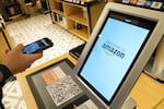 FILE - Daniel Thorpe, of Hoboken, N.J., uses the Amazon app to pay for his purchase at the Amazon 4-star store in the Soho neighborhood of New York, on Sept. 27, 2018.