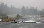 Surfers on a smoky day at the Bend Whitewater Park in September in Bend. Unhealthy air quality from nearby wildfires lasted for several days.