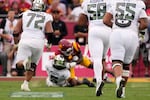 Oregon quarterback Dante Moore, center bottom, takes a hard tackle by lSouthern California inebacker Desman Stephens II, center top, during the first half of an NCAA college football game, Saturday, Sept. 26, 2026, in Los Angeles.