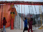 In Ayodhya, women walk past a wooden frame covered in billowing fabric, marigold garlands and images of the Hindu god Hanuman, as workers prepare for an influx of dignitaries ahead of Monday's consecration of the new temple.