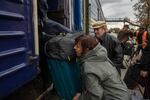 A displaced woman from eastern Ukraine's Donbas region lifts her luggage onto a train that leaves daily for Dnipro from the station in the mining city of Pavlohrad. From Dnipro displaced people are fanning out into western Ukraine and into Europe to stay with relatives.