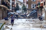 TOPSHOT - Residents are pictured next to cars piled up in a mud-covered street after floods in Picanya, near Valencia, eastern Spain, October 30, 2024. Flooding triggered by torrential rain in Spain's eastern Valencia region has killed 51 people, emergency services said on October 30. (Photo by Jose Jordan / AFP) (Photo by JOSE JORDAN/AFP via Getty Images)