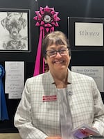 Show Chairman Patti Strand stands in front of the 'Best in Show' winner of the student art contest at the Rose City Classic in Portland, Ore. on January 17, 2026. Strand has been a member of The Dog Fanciers' Association of Oregon, which puts on the event, since 1982.