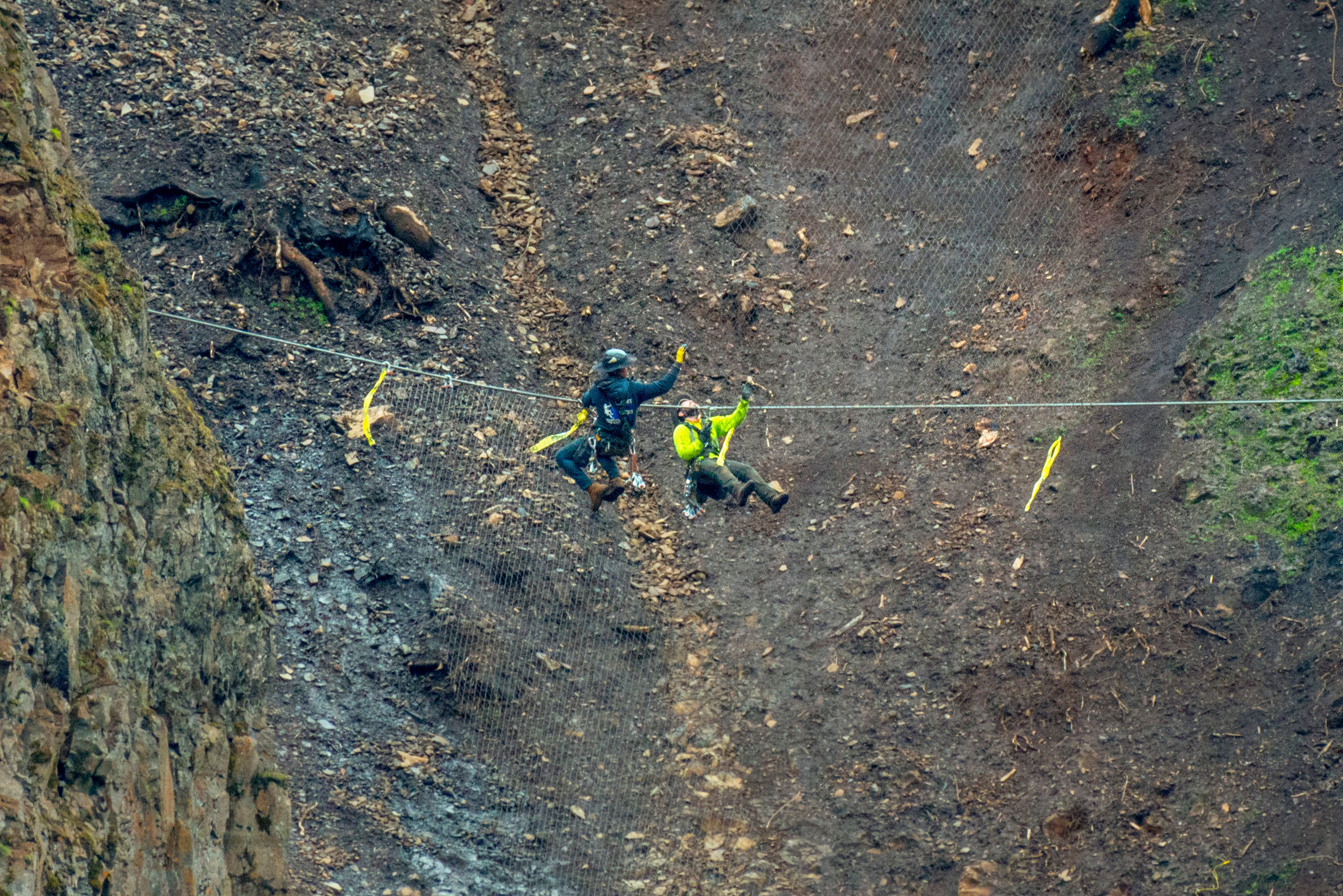 In this February 2022 photo provided by the Oregon Department of Transportation, workers scale cliffsides near Oregon Highway 224 while installing wire mesh to prevent rockslides.