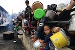 Palestinian children wait to collect food at a donation point in a refugee camp in Rafah in the southern Gaza Strip on December 23, 2023.