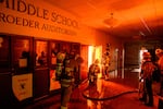 Firefighters prepare to fight flames from inside Eliot Arts Magnet Middle School auditorium as the school burns during the Eaton fire in the Altadena area.