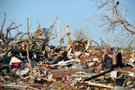 A man sits among the wreckage caused by a series of powerful storms and at least one tornado on March 25, 2023 in Rolling Fork, Mississippi.