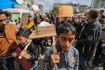 Palestinian children carry banners during a march demanding an end to the war and an end to the famine that citizens suffer from due to the war on Wednesday, March 6, in Rafah, Gaza.