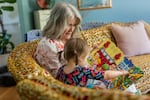 Mary Jo Galusha reads a book to her granddaughter, Robin, 23 months, at her home in Newark, Delaware. The two are sitting on a sofa together.