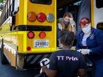 Teachers, Jennifer Scandle, left, and Renee Roberts, right, hand out a lunch to Kelsi Clarke, center, from a school bus.